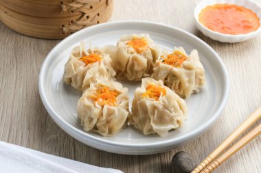 Lezzetli Dim Sum, tabakta servis edilen ev yapımı Çin mantısı, sos ve çubukla. Gri arkaplanda izole edilmiş, kapat.