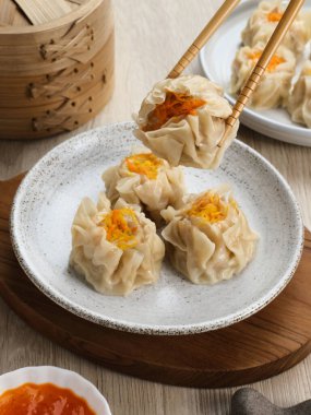 Lezzetli Dim Sum, tabakta servis edilen ev yapımı Çin mantısı, sos ve çubukla. Gri arkaplanda izole edilmiş, kapat.