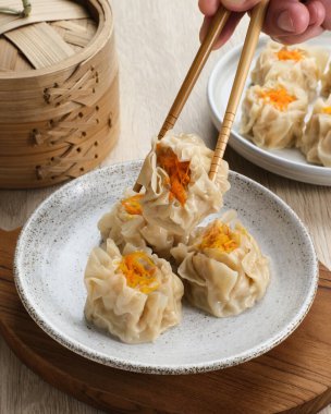Lezzetli Dim Sum, tabakta servis edilen ev yapımı Çin mantısı, sos ve çubukla. Gri arkaplanda izole edilmiş, kapat.