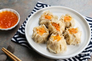 Lezzetli Dim Sum, tabakta servis edilen ev yapımı Çin mantısı, sos ve çubukla. Gri arkaplanda izole edilmiş, kapat.