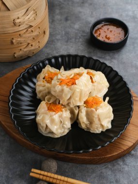 Lezzetli Dim Sum, tabakta servis edilen ev yapımı Çin mantısı, sos ve çubukla. Gri arkaplanda izole edilmiş, kapat.