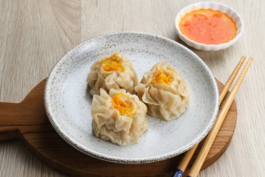 Lezzetli Dim Sum, tabakta servis edilen ev yapımı Çin mantısı, sos ve çubukla. Gri arkaplanda izole edilmiş, kapat.