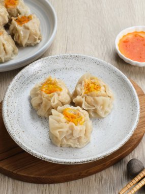 Lezzetli Dim Sum, tabakta servis edilen ev yapımı Çin mantısı, sos ve çubukla. Gri arkaplanda izole edilmiş, kapat.