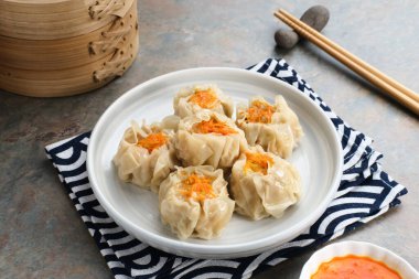 Lezzetli Dim Sum, tabakta servis edilen ev yapımı Çin mantısı, sos ve çubukla. Gri arkaplanda izole edilmiş, kapat.