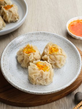 Lezzetli Dim Sum, tabakta servis edilen ev yapımı Çin mantısı, sos ve çubukla. Gri arkaplanda izole edilmiş, kapat.