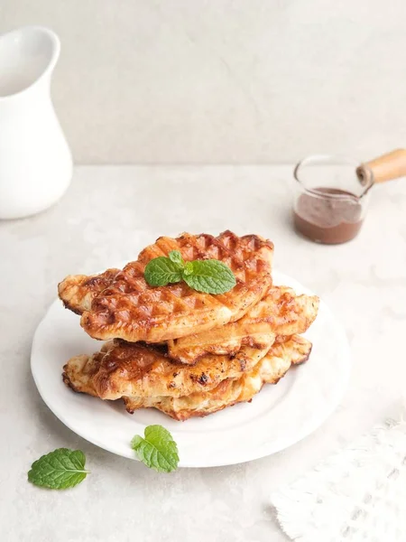 stock image Stack of Caramelized Croissant Waffle or Croffle served in white plate on grey background. Close up, copy space.