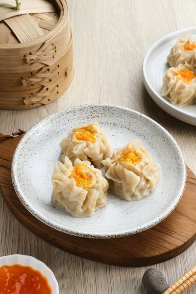 Lezzetli Dim Sum, tabakta servis edilen ev yapımı Çin mantısı, sos ve çubukla. Gri arkaplanda izole edilmiş, kapat.