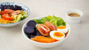 Sağlıklı salata kasesi, sebze havucu, marul, domates, tatlı patates ve susam soslu yumurta karışımı.