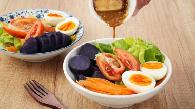 Sağlıklı salata kasesi, sebze havucu, marul, domates, tatlı patates ve susam soslu yumurta karışımı.