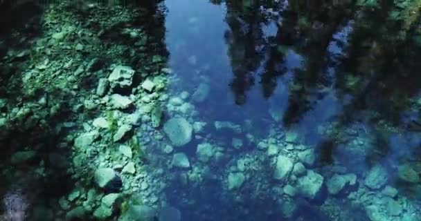 Een vliegende overheen helder blauw water in het woud laag — Stockvideo