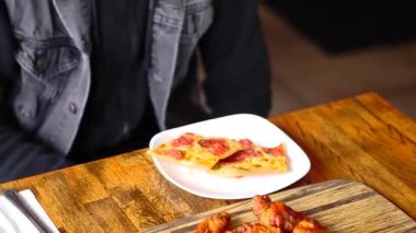 Tahta bir masanın üstünde duran bir dilim pizza.