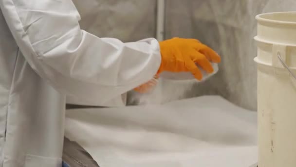 Чоловік струшує білий порошок через фільтр в промисловій лабораторії — стокове відео