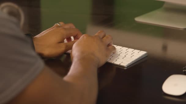 Eine Person sitzt am Schreibtisch vor einer Tastatur — Stockvideo