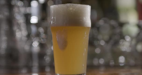 Un vaso de cerveza sobre una mesa — Vídeos de Stock