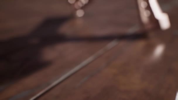Uma cruz de ouro rosa religiosa caindo sobre painéis de piso de madeira — Vídeo de Stock