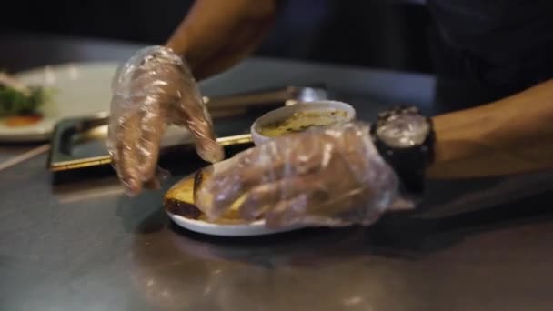 A šéfkuchař posuvný talíř francouzské cibulové polévky a opékaný chléb číšníkovi na kuchyňské lince — Stock video