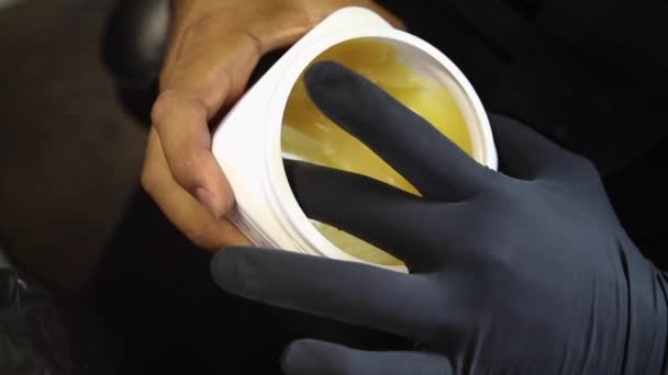 A Close up of tattoo artist scooping out petroleum jelly with gloved fingers — 图库视频影像