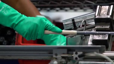 Bir fabrika çalışanı yavaş çekim üretim tesisinde yepyeni golf sopaları kullanıyor.