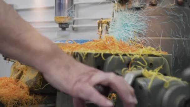 Ein männlicher Arbeiter, der in einer Werkstatt an einer Industriedrehmaschine arbeitet, schnitzt einen Block aus blauem Kunststoff heraus — Stockvideo