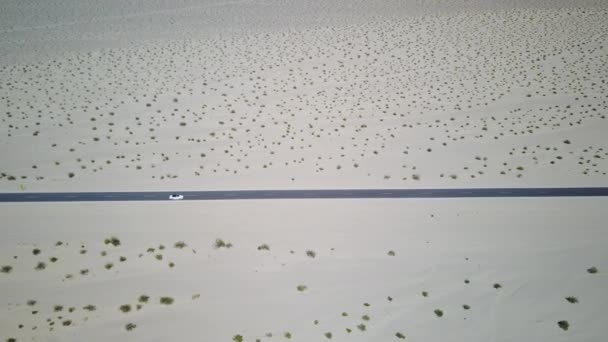 Белый кабриолет проезжает мимо по дороге в плоском пустынном пейзаже — стоковое видео