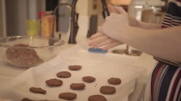 Uma mulher colocando biscoitos não cozidos na panela na ilha da cozinha — Vídeo de Stock