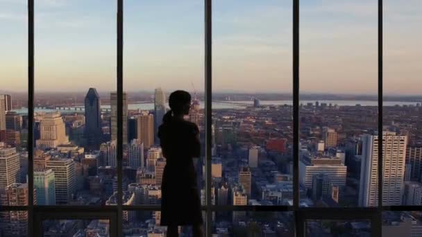 Una mujer Silhouette mirando por la ventana de la oficina en el horizonte de Montreal — Vídeos de Stock