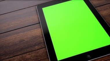 Masanın üzerinde yeşil ekranı gösteren tabletin sol slaytı