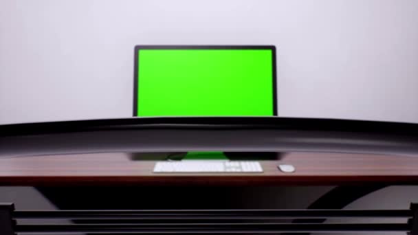 Una sedia da ufficio spinta in più per rivelare il computer desktop che visualizza lo schermo verde sulla scrivania — Video Stock