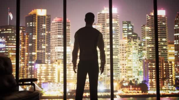 Un homme Silhouette regardant par la fenêtre du bureau à san diego califronia skyline — Video