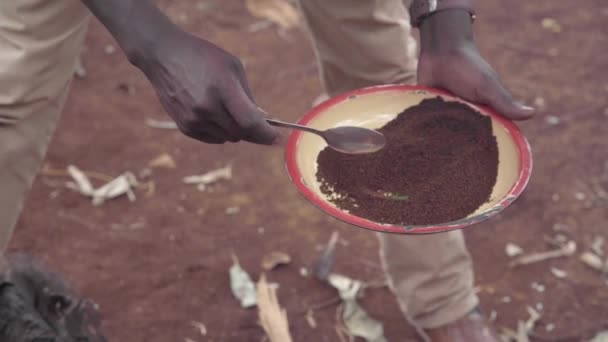 Um homem africano recolhe café em panela de água fervente — Vídeo de Stock