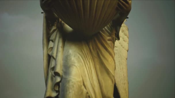 Um anjo de pedra fêmea segurando estátua shell perto da borda do penhasco céu nublado dinâmico — Vídeo de Stock