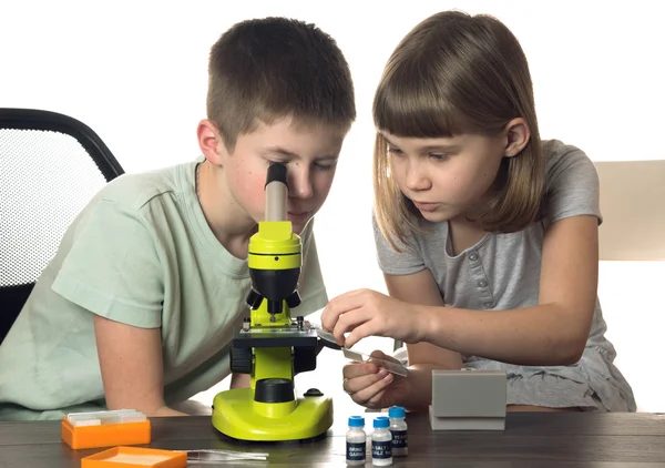 Dívka a chlapec s mikroskopem izolovaných na bílém pozadí — Stock fotografie