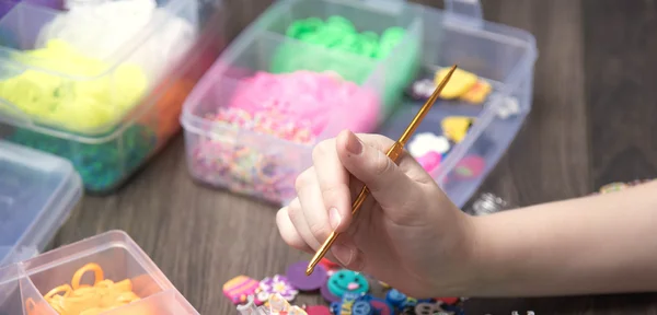 Children's hands are weaving figures out colored rubbers — Stock Photo, Image