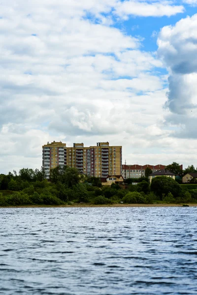 За річкою висотна будівля на фоні блакитного неба і хмар — стокове фото