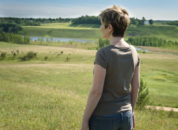 Femme solitaire debout avec son dos sur le champ vert — Photo