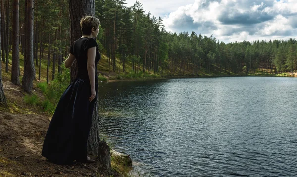 Silueta de mujer solitaria cerca del lago del bosque —  Fotos de Stock