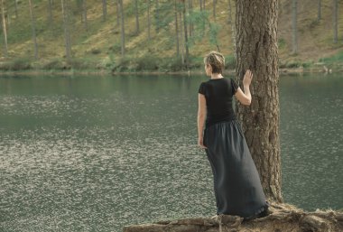 mesafe içine görünüyor ve Gölü kıyısında uzun etek ayakta yalnız genç kadın