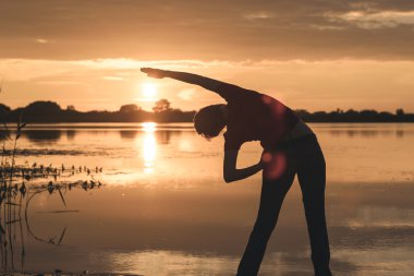 ince kadın göl kıyısında günbatımı yapıyor