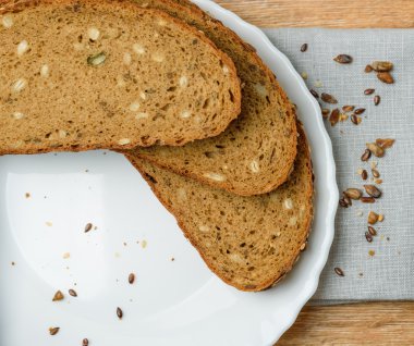 Ahşap bir masa üzerinde plaka ile dilimlenmiş taze kepekli ekmek