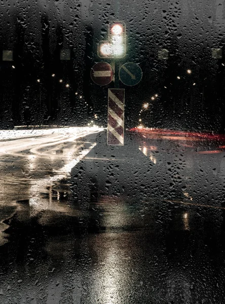 Нічний вид на вулицю через скло з дощовими краплями — стокове фото