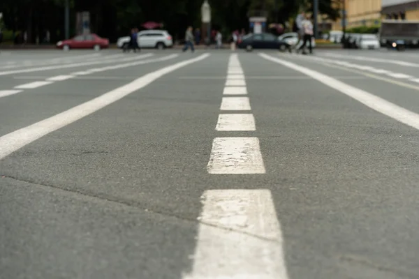 Marcas en la carretera contra el fondo de las personas en desenfoque —  Fotos de Stock