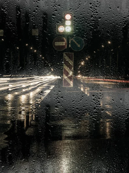 Nocny widok z ulicy przez szybę z deszczu — Zdjęcie stockowe
