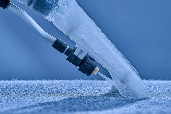 Washing carpet with vacuum cleaner close-up on a blue background. Royalty Free Stock Photos