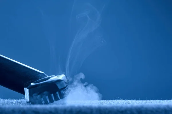Home cleaning. Steam carpet cleaning on blue background. Photo with copy space. Stock Picture