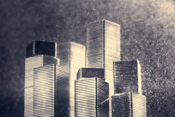 Horizontal shot of skyscrapers made of stapler staples illuminated with bright light on a dark background in a blur.