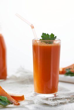 Beyaz arka planda maydanozlu havuç suyu bardağı..