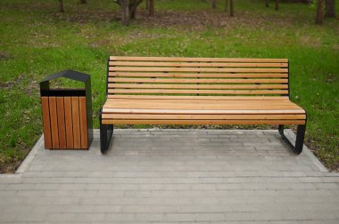 Parktaki ahşap bank ve çöp kutusunun yatay görüntüsü..