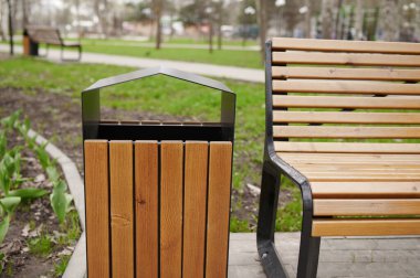 Tahta çöp tenekesinin yatay görüntüsü ve bahar parkında bank..