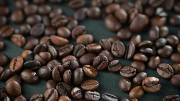 Les grains de café sont éparpillés sur la table noire. Contexte en flou. — Video