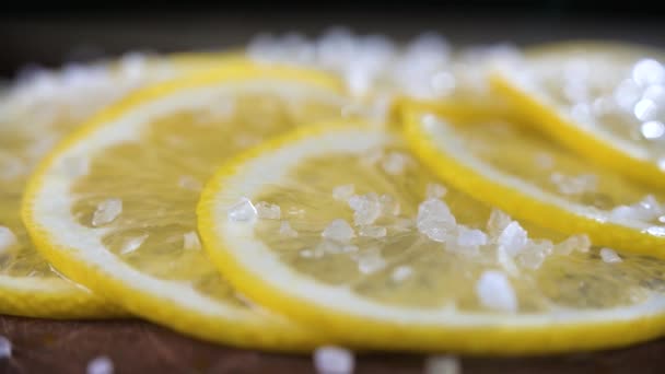 Limón en rodajas espolvoreado con sal gruesa de cerca. Antecedentes borrosos. — Vídeos de Stock